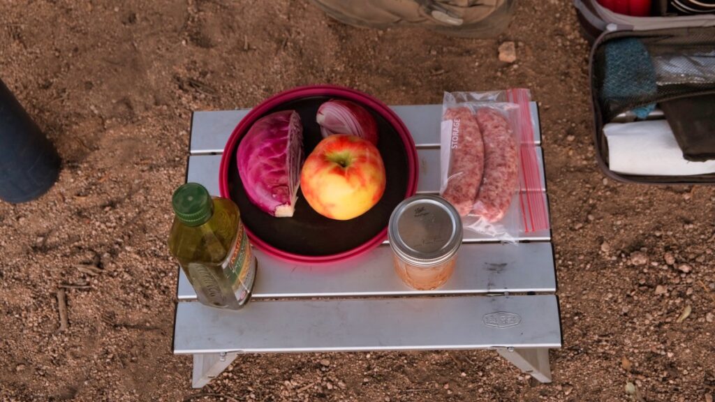 dinner ingredients sausga apple cabbage and cider vinegar on GSI folding table